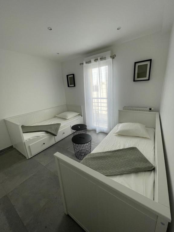 two beds in a white room with a window at Appartement 4P, au pied de toute commodité in Créteil