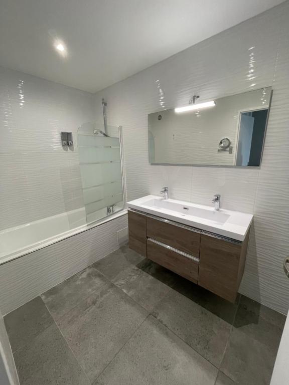 a bathroom with a sink and a mirror and a tub at Appartement 4P, au pied de toute commodité in Créteil