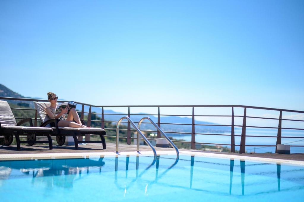 zwei Frauen auf einer Bank neben einem Pool in der Unterkunft Senso Panorama Luxury Villa in Kalamata