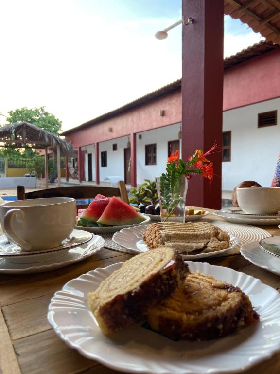 a wooden table with plates of bread and coffee and fruit at Casa da Lagoa in Jijoca de Jericoacoara