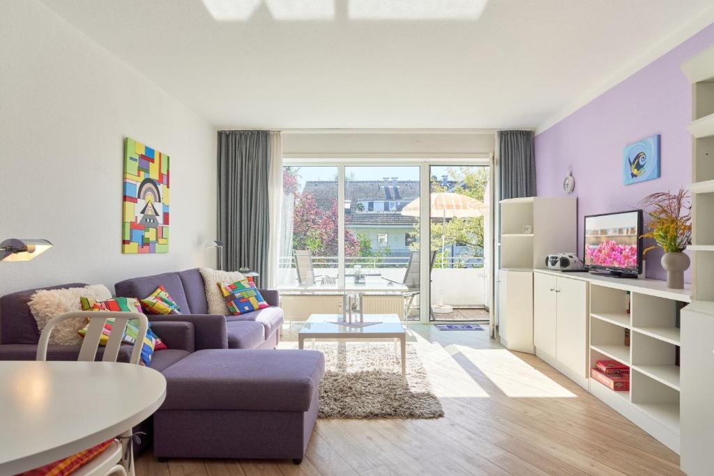 ein Wohnzimmer mit einem lila Sofa und einem Tisch in der Unterkunft NeuKlosterhof App. 18 in Pelzerhaken