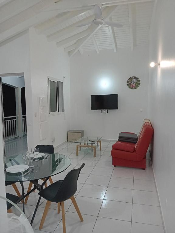 sala de estar con sofá rojo y mesa de cristal en Maison dans les hauteurs, en Le Gosier