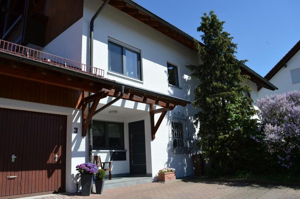 une maison blanche avec une véranda et un garage dans l'établissement Ferienwohnung Alb-Traum, à Erkenbrechtsweiler