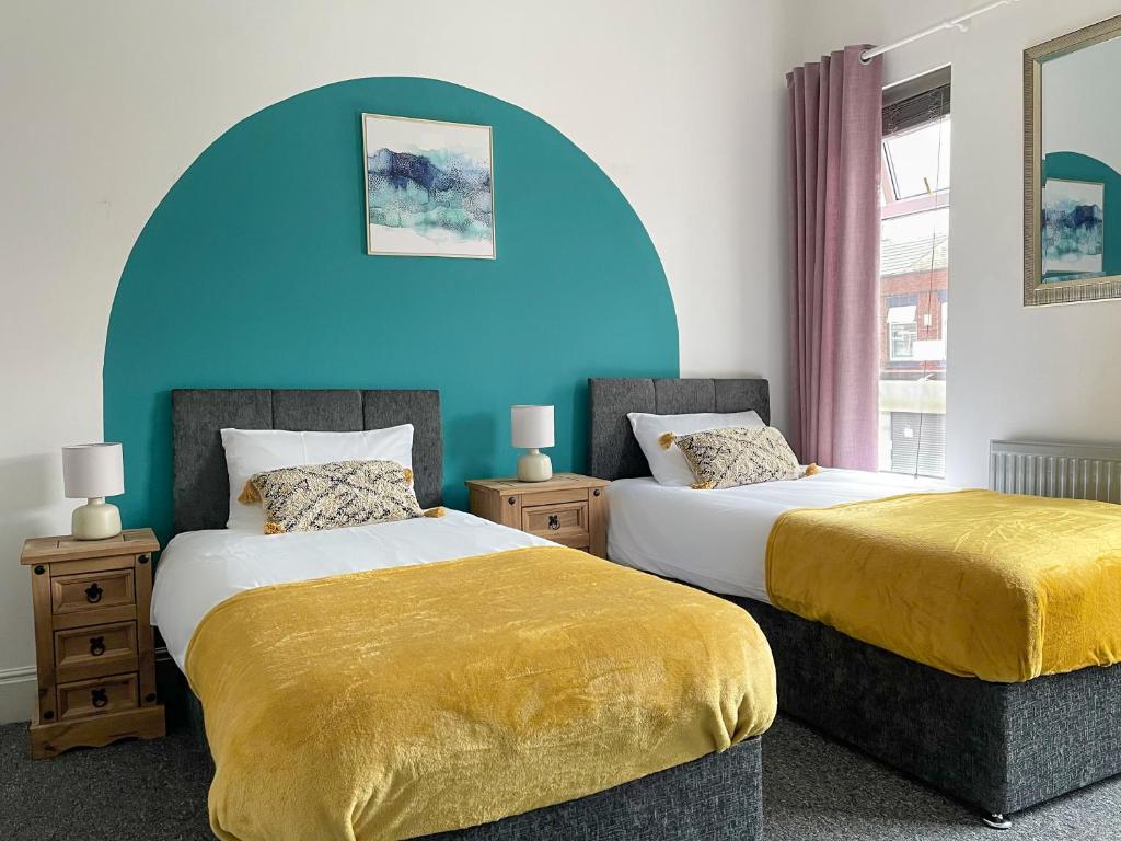 Duas camas num quarto com uma parede azul em Large House near MediaCity, sleeps 13 with FREE Parking and Fast WIFI - Contractor and Long Stay Friendly - by IRWELL STAYS em Manchester
