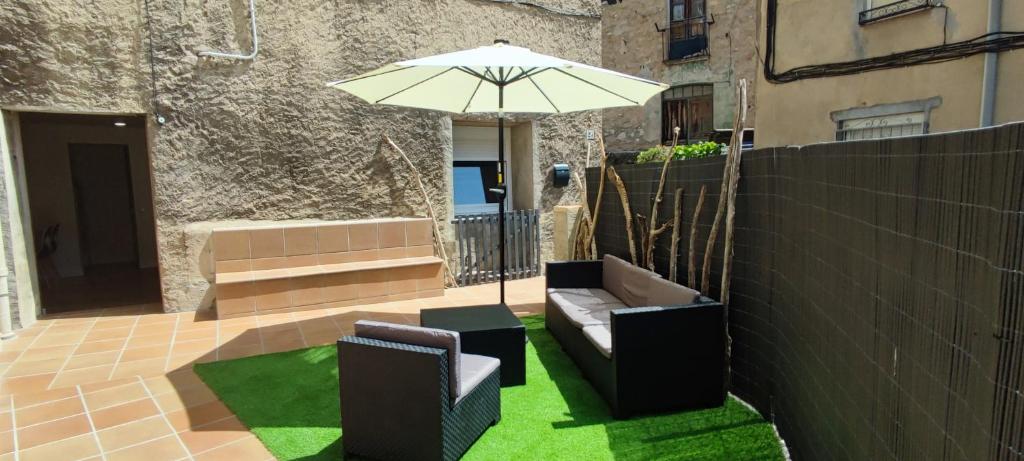 un patio con sombrilla, sillas y césped en La Bombonera del Berguedà, en Sant Jordi de Cercs