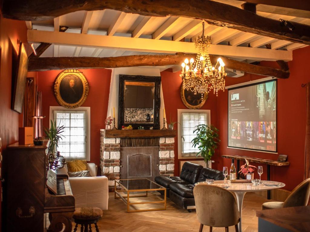 una sala de estar con paredes rojas y una lámpara de araña. en Les Arts - Cocon romantique en Baie de Somme, en Boismont