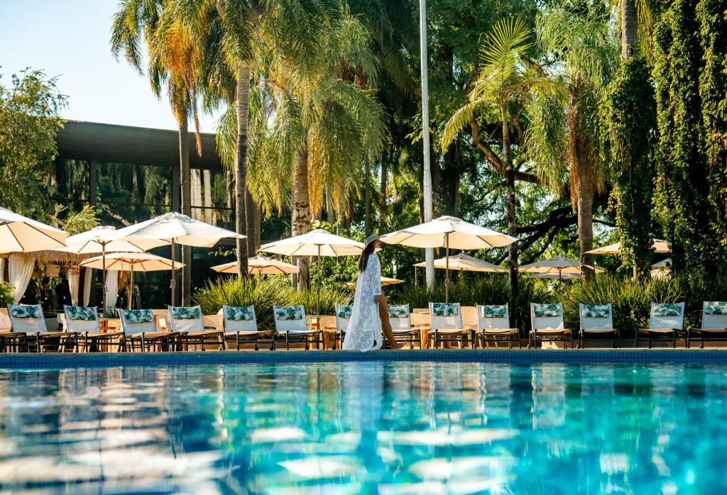 uma piscina do hotel com cadeiras e guarda-sóis em Vivaz Cataratas Hotel Resort em Foz do Iguaçu