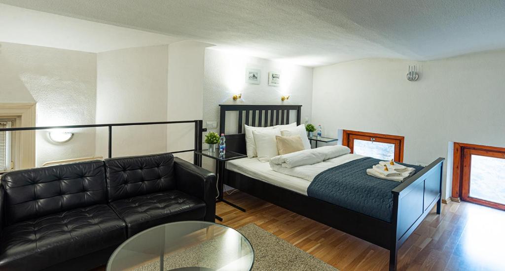 een slaapkamer met een bed, een bank en een tafel bij Cosy Corner - Entire Apartment near Oktogon in Boedapest