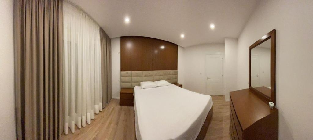 een slaapkamer met een groot wit bed en een spiegel bij Royal Seaview Apartment in Durrës