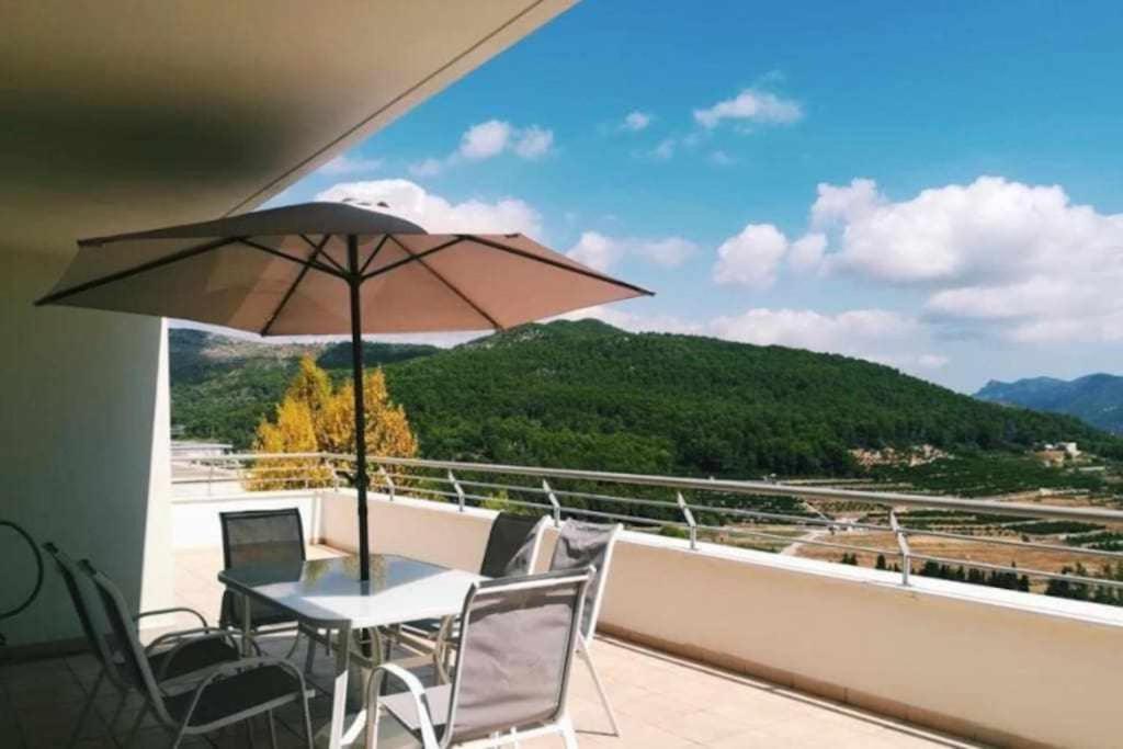 una mesa y sillas con una sombrilla en el balcón en Mar Sol y Montaña with Airco en Ador