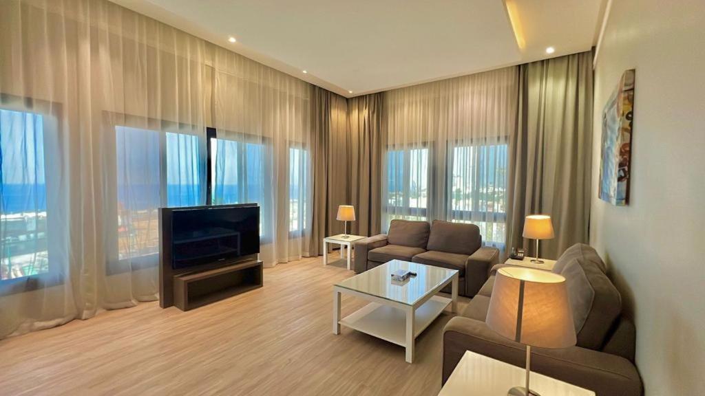 ein Wohnzimmer mit einem Sofa und einem TV in der Unterkunft Loren Suites Corniche in Dschidda