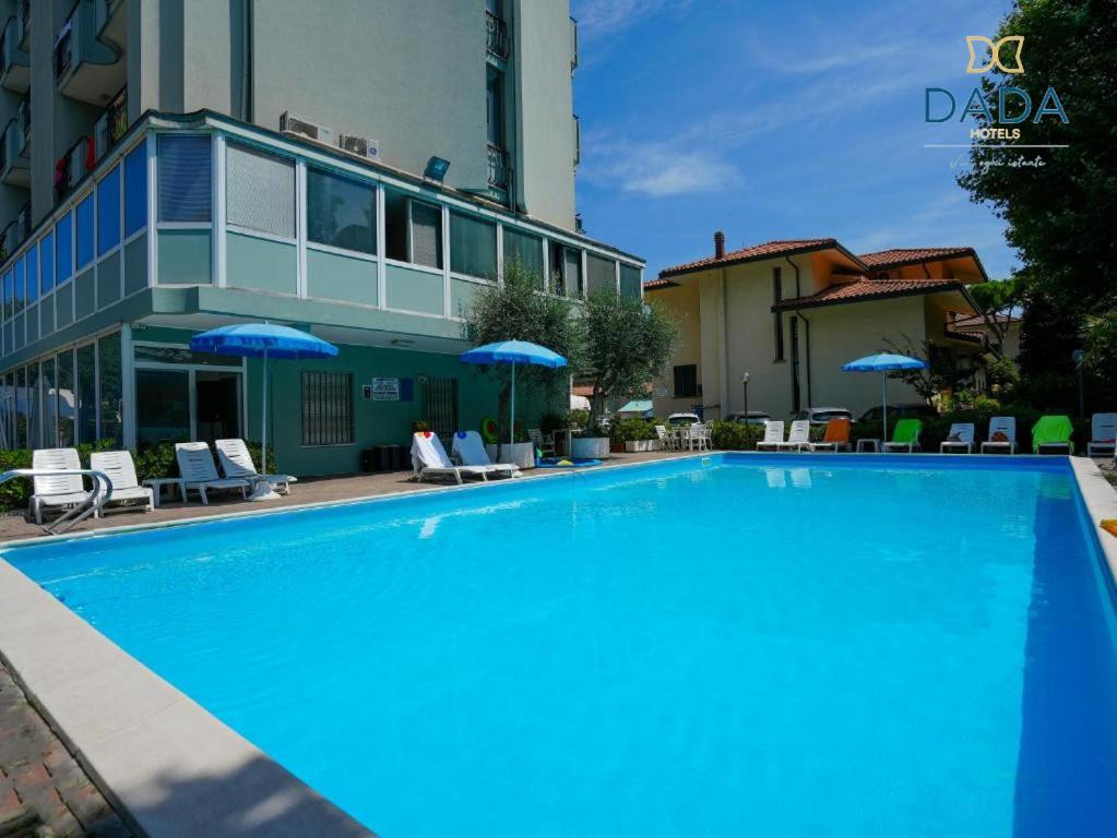 a large blue swimming pool in front of a building at Dasamo Hotel - Dada Hotels in Rimini