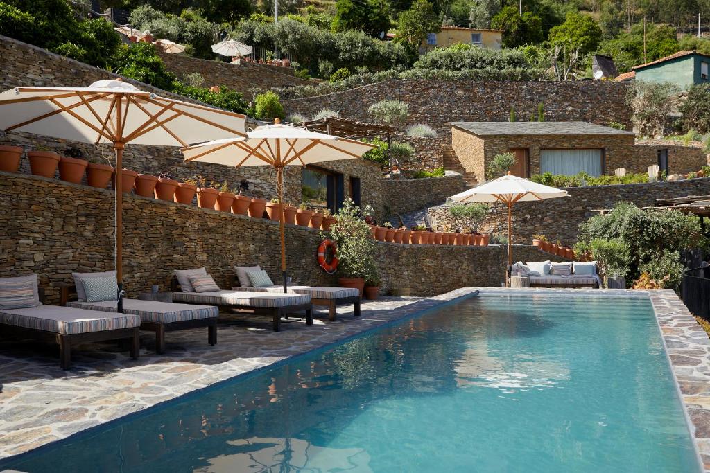 - une piscine avec des chaises et des parasols à côté d'un bâtiment dans l'établissement DOURWIN - Riverside Suites - Adults Only, à Penafiel