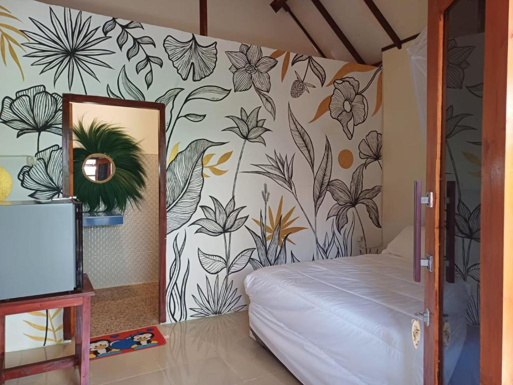 1 dormitorio con 1 cama y una pared con flores en Black Sweet Bungalow, en Gili Air