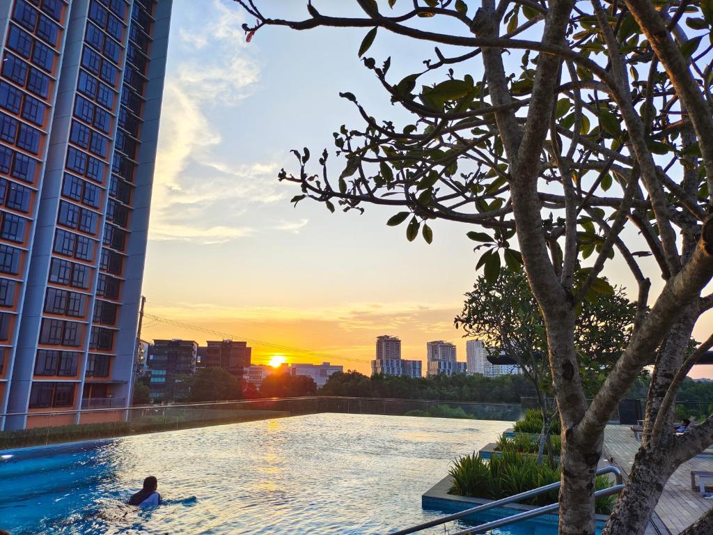 a person swimming in a swimming pool on top of a building at Kanvas Soho Cyberjaya/Netflix/Gym/Jacuzzi/KLIA in Cyberjaya
