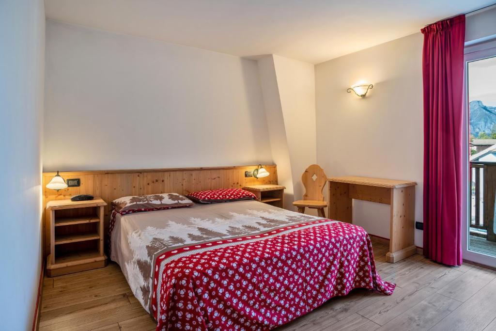 een slaapkamer met een bed met een rood-witte deken bij Giongo Residence Aparthotel 101 in Lavarone