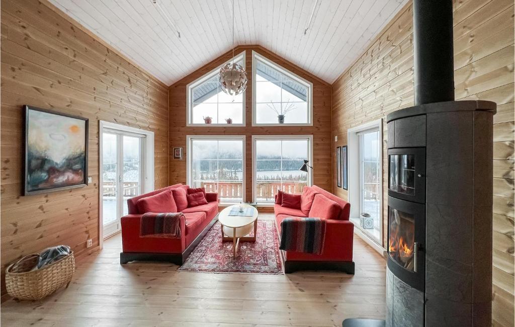 a living room with two red chairs and a fireplace at Stunning Home In Nord Torpa With Wifi in Nord Torpa