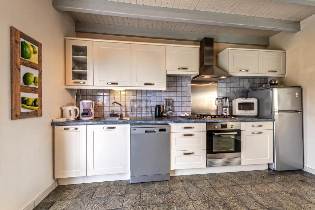 a kitchen with white cabinets and stainless steel appliances at Meublé De Tourisme Acanthe in Camaret-sur-Mer