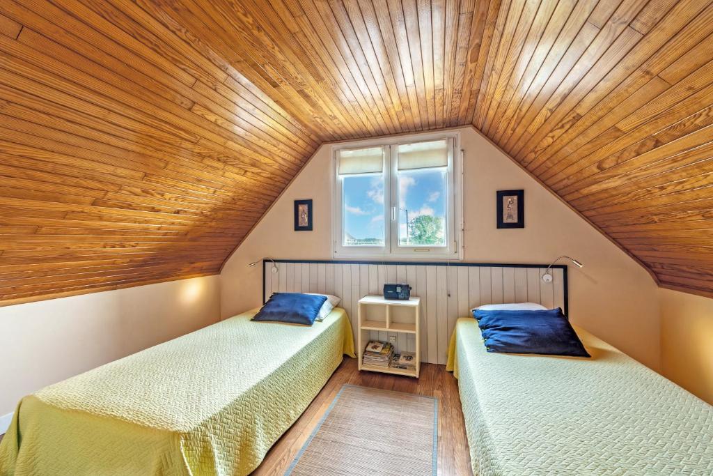 two beds in a room with a wooden ceiling at Meublé De Tourisme Acanthe in Camaret-sur-Mer
