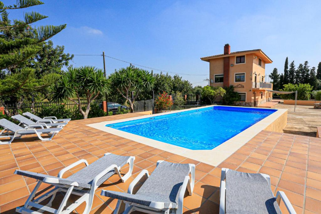 una piscina con sedie a sdraio e una casa di La Higuerita ONLY FAMILES a Vilaseca de Solcina