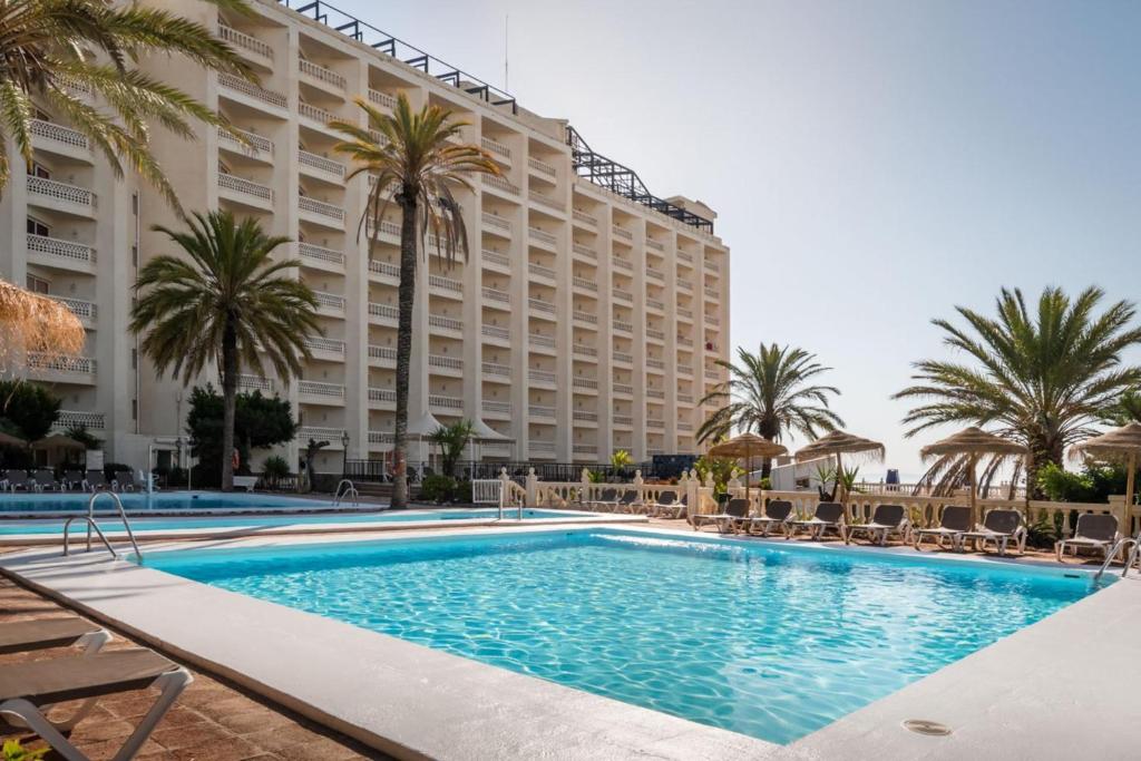 a pool in front of a hotel with palm trees at Hotel Portomagno by ALEGRIA in Aguadulce