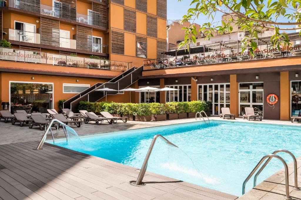 une piscine en face d'un bâtiment dans l'établissement ALEGRIA Plaza Paris 4*Sup, à Lloret de Mar