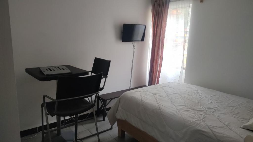 1 dormitorio con 1 cama y escritorio con 2 sillas en Cómoda y tranquila recámara cerca de Aeropuerto Benito J baño compartido, en Ciudad de México