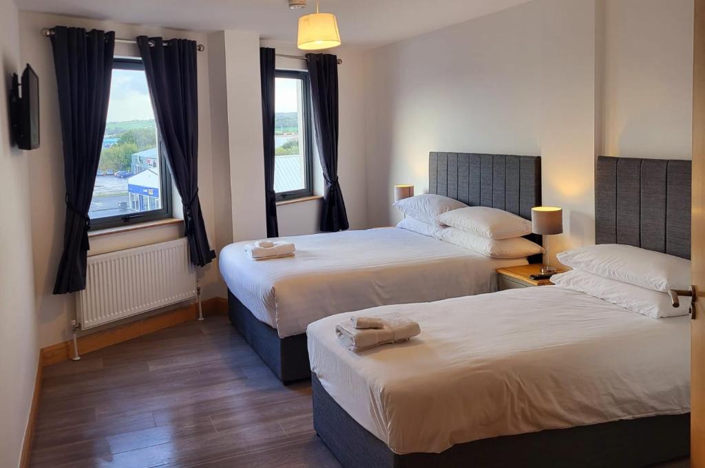 Habitación de hotel con 2 camas y ventana en Wild Atlantic Apartments Port House Letterkenny en Letterkenny