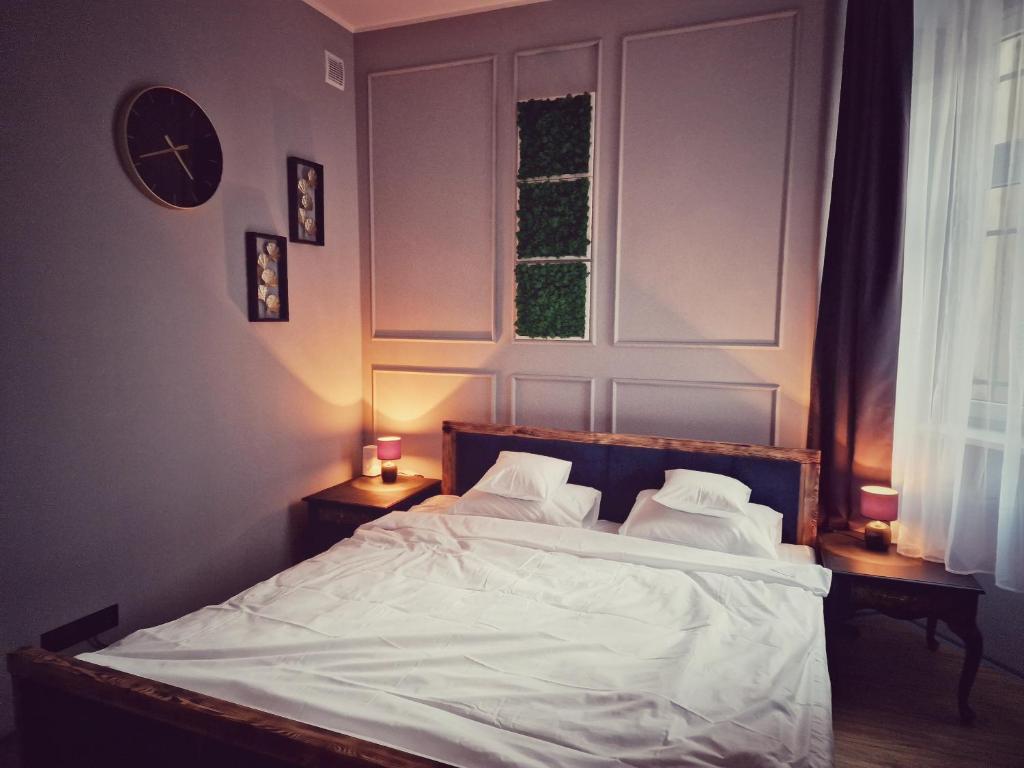 a bedroom with a bed with white sheets and a clock at Apartamenty Toskania No.2 in Poznań