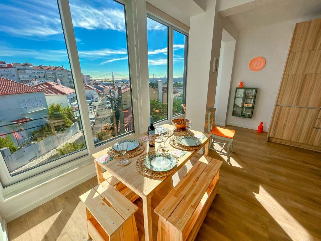 einen Tisch und Stühle in einem Zimmer mit großen Fenstern in der Unterkunft Belém River Apartment View in Lissabon
