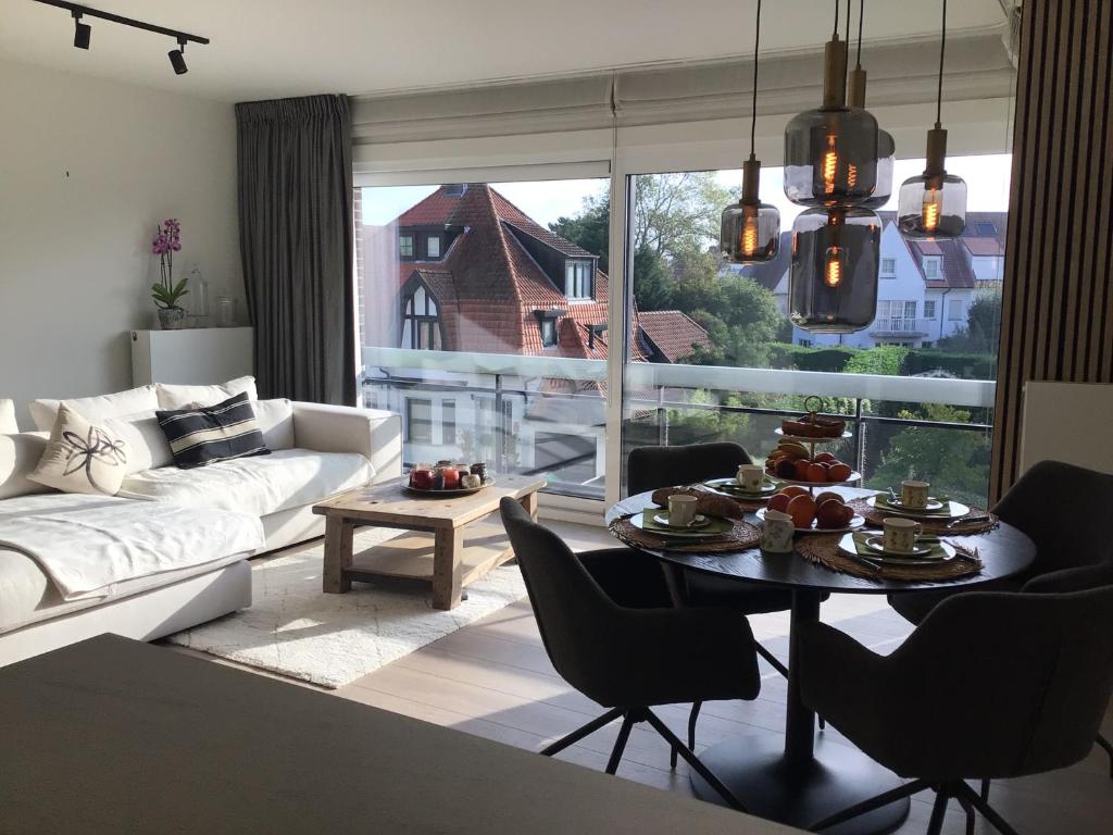 een woonkamer met een witte bank en een tafel met stoelen bij Cosy Cottage Knokke in Knokke-Heist