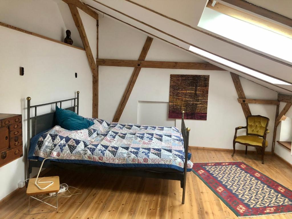 een slaapkamer met een bed en een stoel op zolder bij Finca in Brandenburg Ferienhaus mit Sauna in Baruth