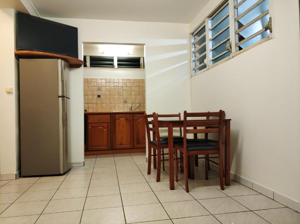 a kitchen with a table and chairs and a refrigerator at Appartement d&#39;une chambre avec jardin clos et wifi a Le Lamentin in Le Lamentin