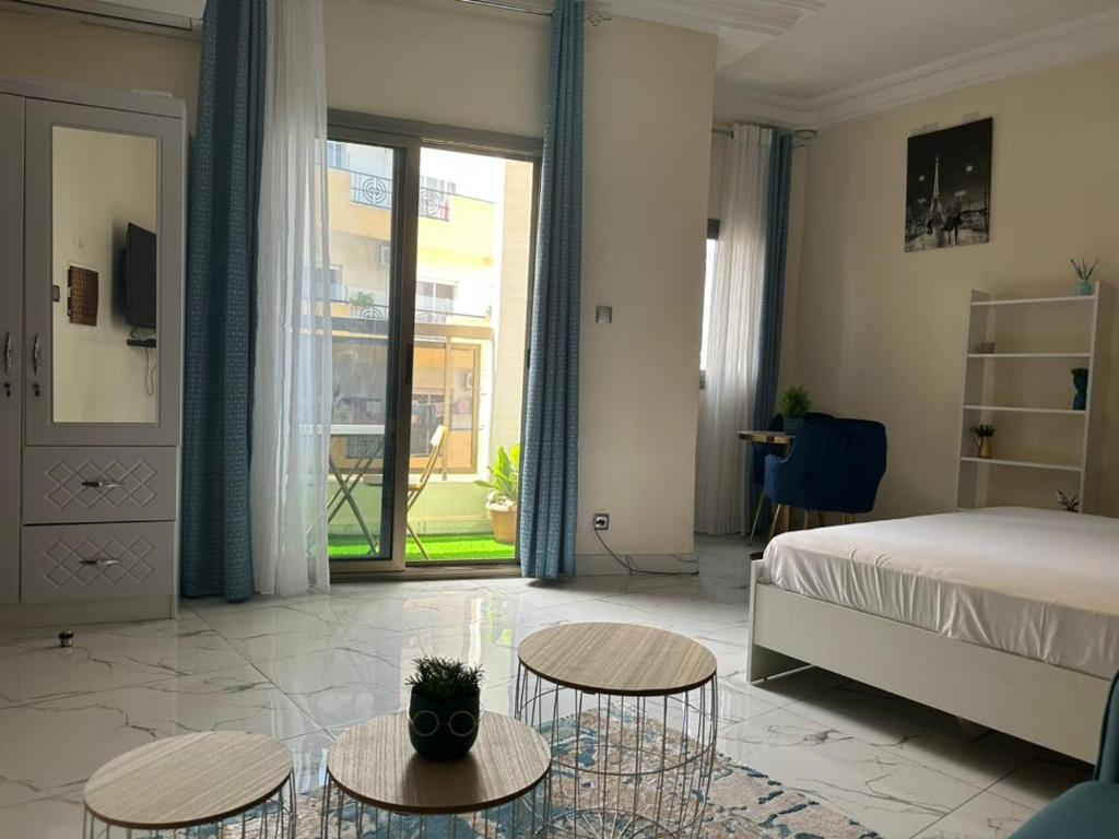 a bedroom with a bed and two tables and a window at Le doux refuge in Dakar