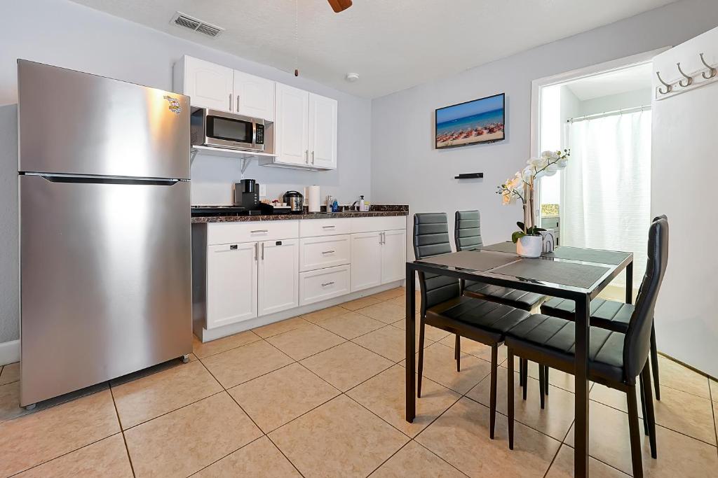 a kitchen with a table and a stainless steel refrigerator at JetPad Tampa Modern studio near Busch Gardens & Airport in Tampa
