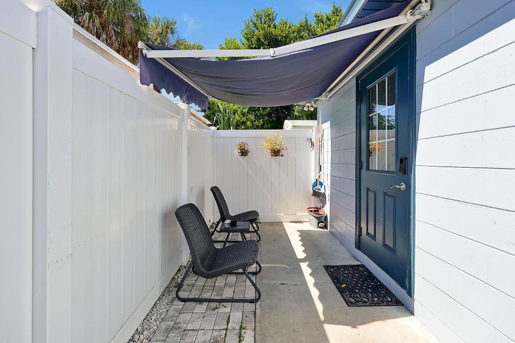 2 chaises assises sur une terrasse couverte avec une porte bleue dans l'établissement Comfortable private room in Tampa: The Wanderlust, à Tampa