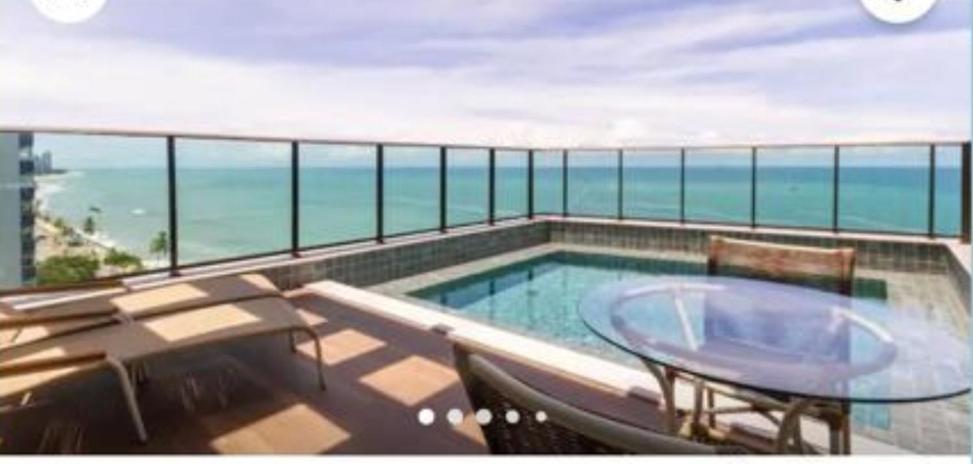 einen Balkon mit einem Pool, einem Tisch und Stühlen in der Unterkunft Boa Viagem beach 503 in Recife