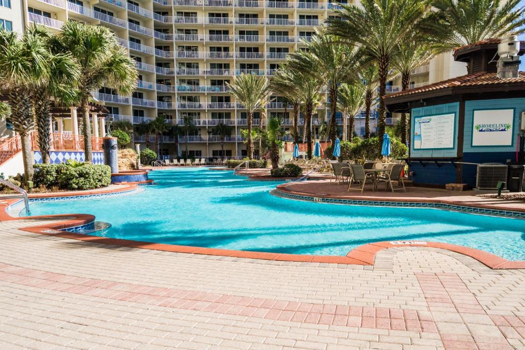 a swimming pool with palm trees and a large building at Shores of Panama #1921 by Nautical Properties in Panama City Beach