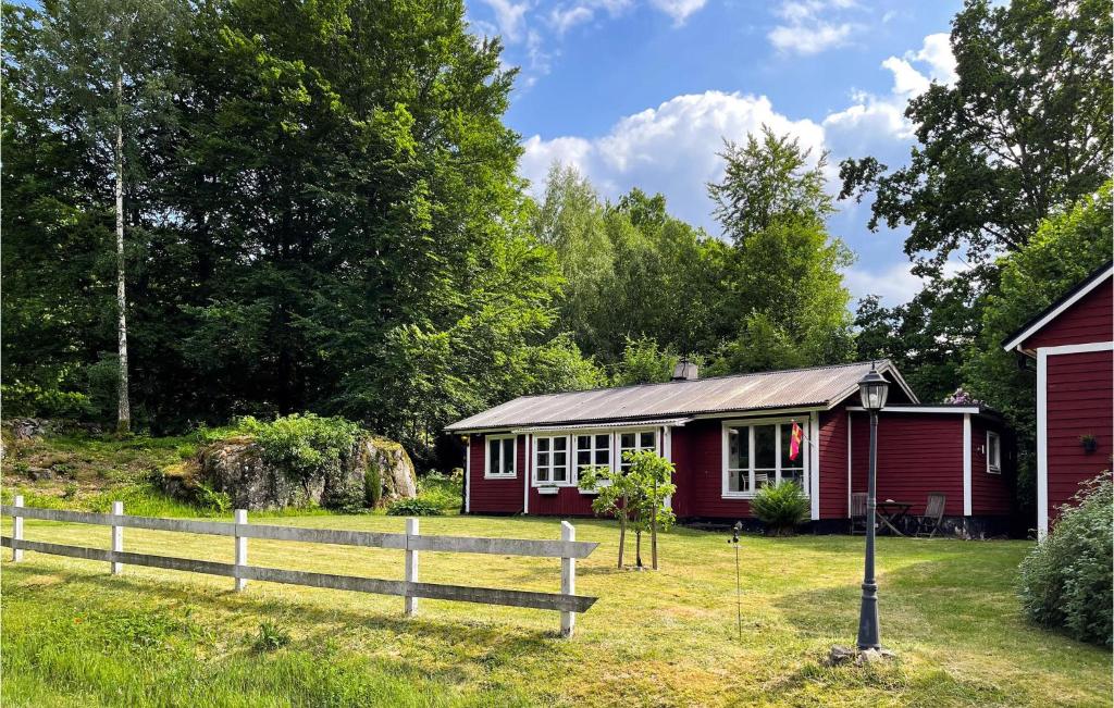 eine rote Hütte mit einem Zaun davor in der Unterkunft Nice Home In Tyringe With House A Panoramic View in Tyringe