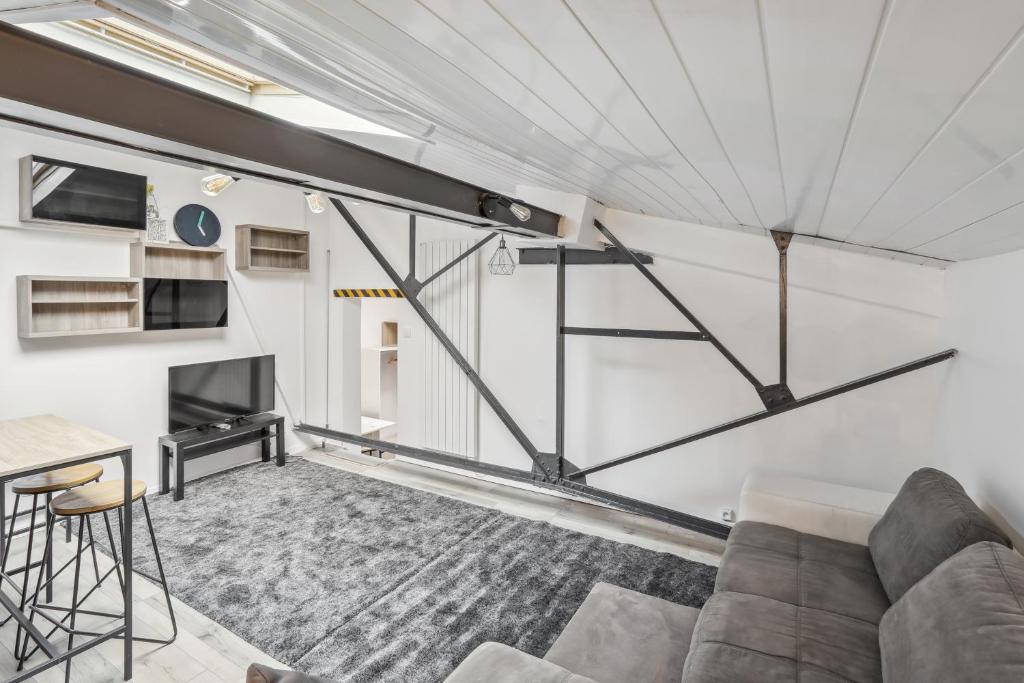 ein Wohnzimmer mit einem Sofa und einem TV in der Unterkunft Loft Paisible à Argenteuil / La défense/Beam in Argenteuil