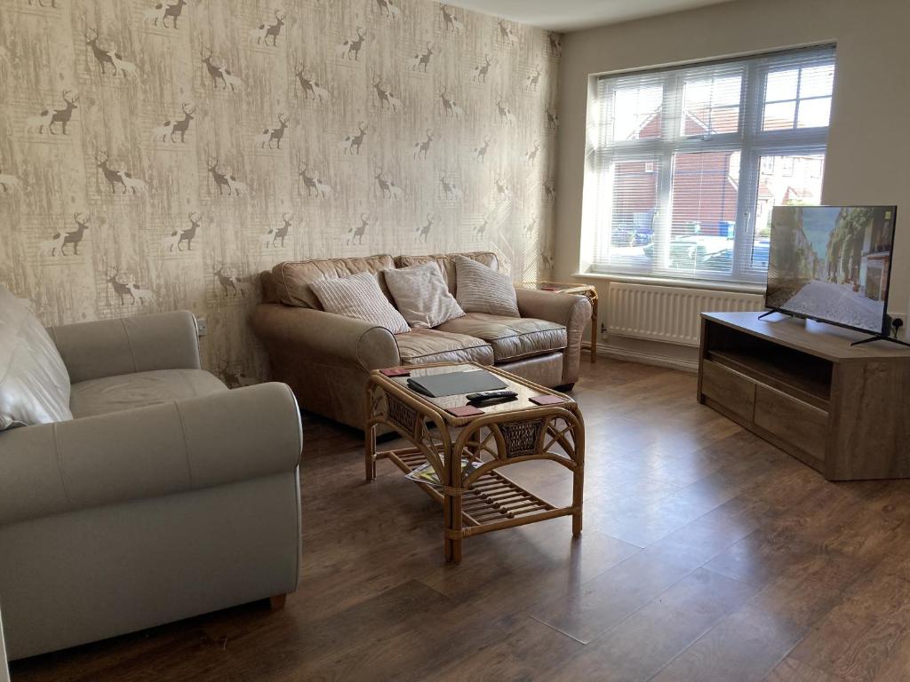 a living room with a couch and a table and a tv at Quiet 3 bed semi with off street parking in Bingham