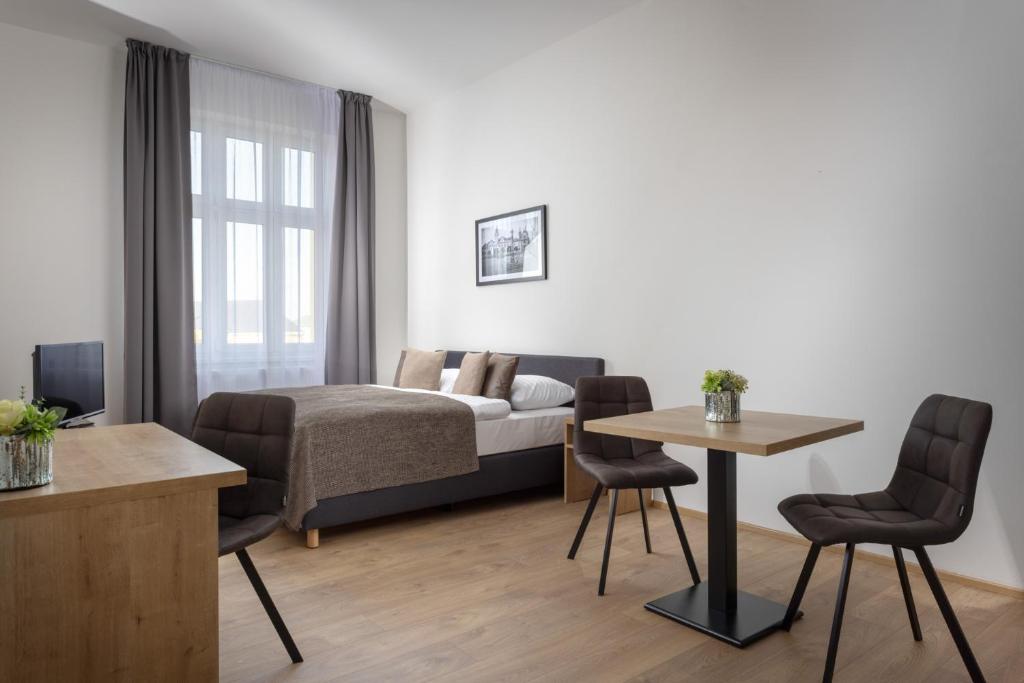 - une chambre avec un lit, une table et des chaises dans l'établissement Residence Morris Mladá Boleslav, à Mladá Boleslav