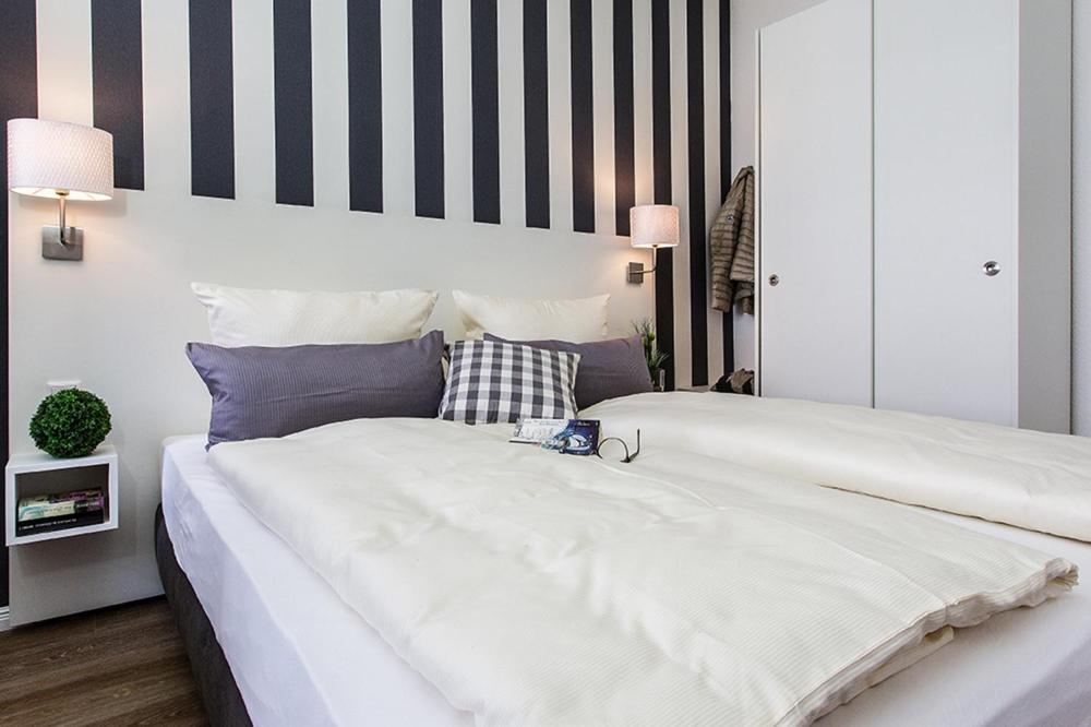 1 dormitorio con 1 cama blanca grande y pared a rayas en Woge2 Appartement 10, en Borkum