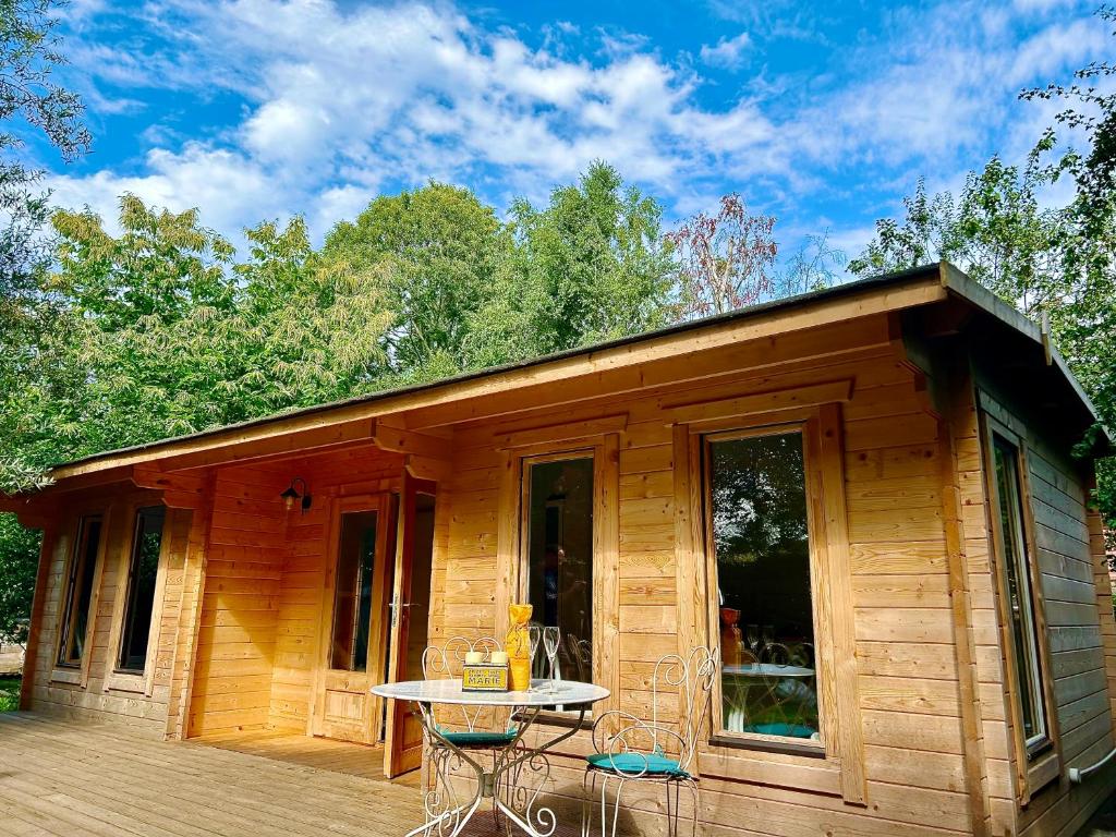 eine kleine Holzhütte mit einem Tisch auf einer Terrasse in der Unterkunft Driftwood Dreams Garden Cabin in Lyminster