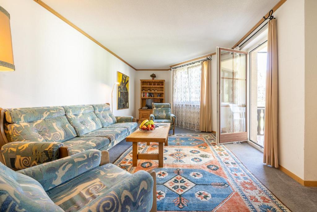 een woonkamer met een bank en een tafel bij 7202 Zweckmaessig eingerichteten Wohnung mit gedecktem Balkon in Vulpera