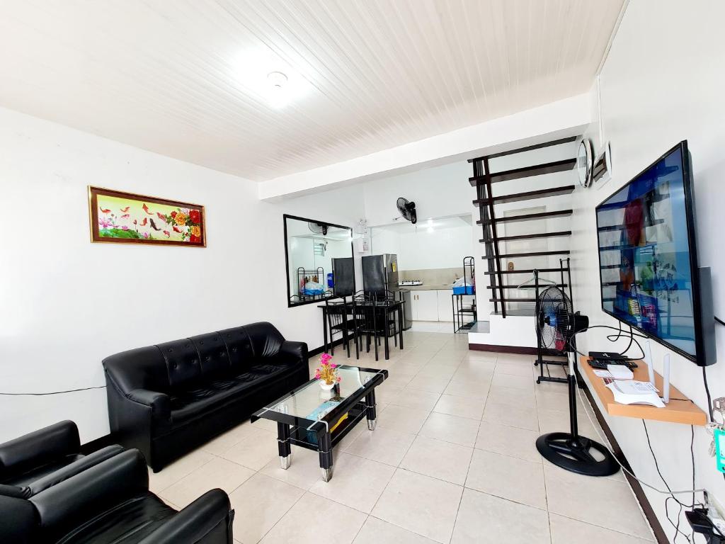 a living room with a black couch and a tv at Vacation Transient Guest House Rental Calapan City L43 in Calapan