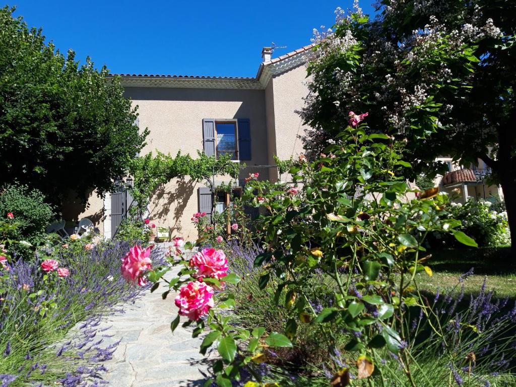 a garden in front of a house with flowers at Le Clos du Verger in La Motte-du-Caire