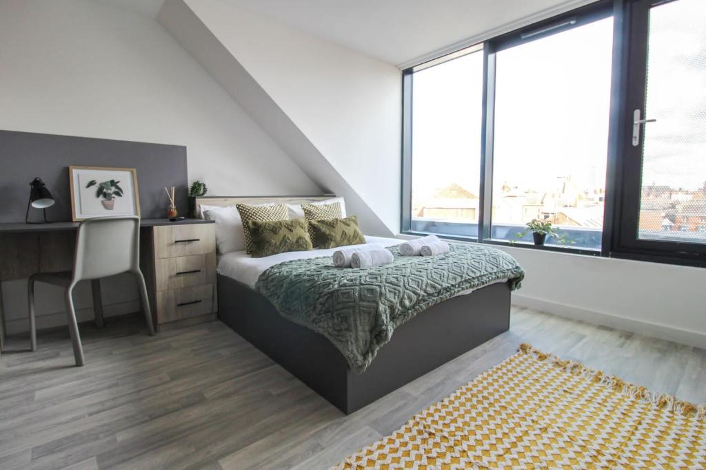 um quarto com uma cama, uma secretária e janelas em The Nest LE1 em Leicester