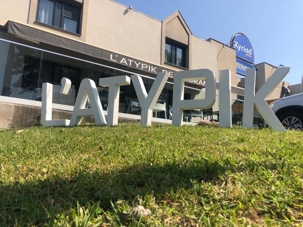 a sign in the grass in front of a building at Hotel Restaurant Kyriad Brive Centre in Brive-la-Gaillarde