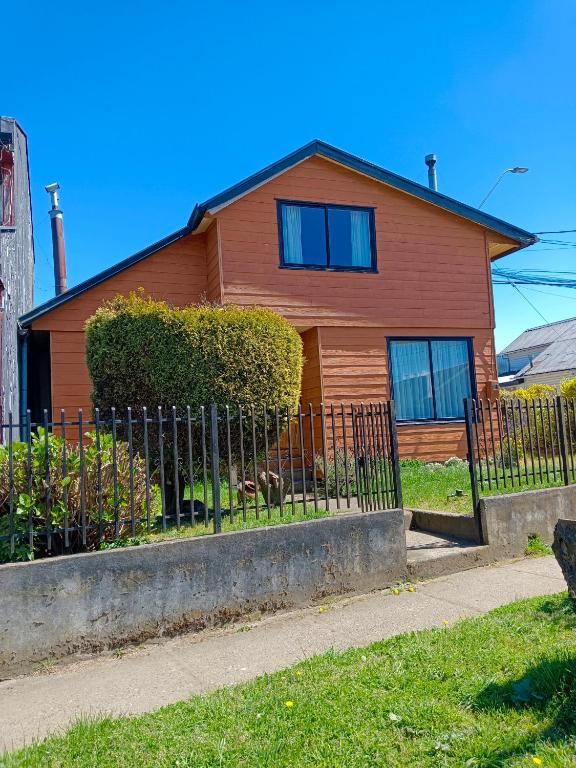 una casa marrón con una valla delante de ella en Calor y amor de hogar chilote, en Castro
